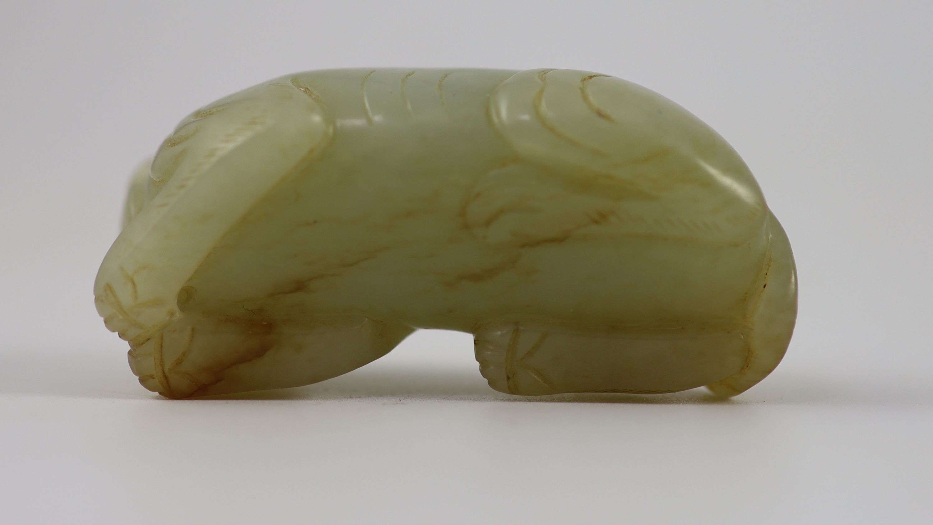 A Chinese pale celadon and russet jade figure of a lion dog, 6.2 cm long